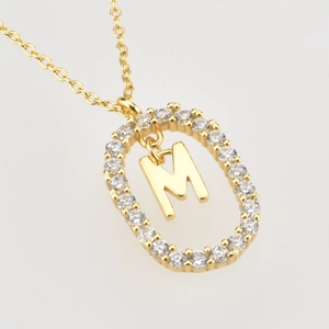 Detailed close-up of 18K gold letter M pendant with sparkling white cubic zirconia stones