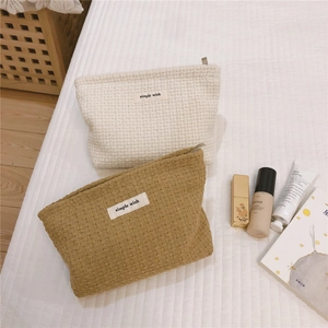 Detail view of waffle texture makeup pouches in cream and yellow with zipper closure