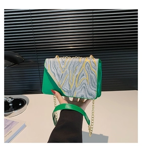 Close-up of green and gold geometric crossbody bag with luxury gold chain strap details
