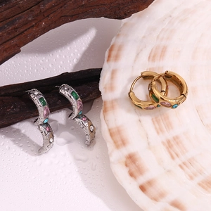 Détail de créoles en or 18 carats et argent avec zircons colorés sur des coquillages