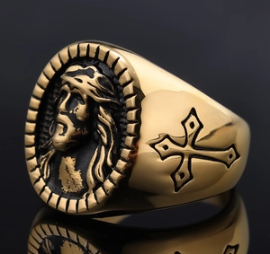Macro detail of gold religious ring featuring Jesus relief and side cross engraving