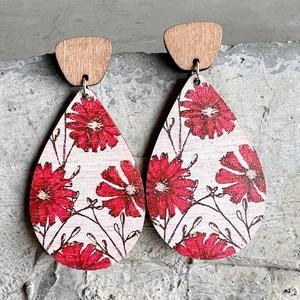 Bohemian teardrop wooden earrings with red floral pattern on textured stone background