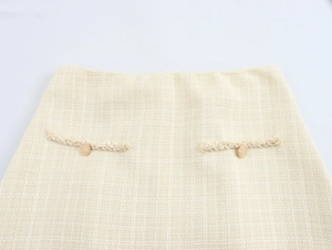Détails de la mini-jupe en tweed beige avec taille haute et boutons dorés