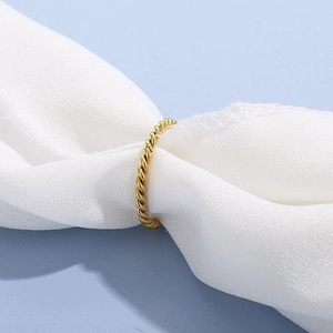 Minimalist golden titanium steel twisted rope ring nestled in white chiffon fabric