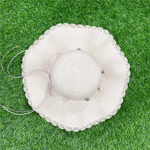 Détail du chapeau de paille tissé avec ruban perlé et bordure en dentelle festonnée