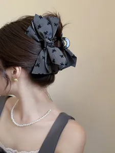 Dettaglio macro della molletta per capelli in tessuto grigio con motivi a fiocco nero