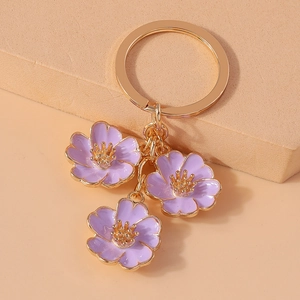 Detailed macro view of three purple enamel flower pendants on a golden metal keychain