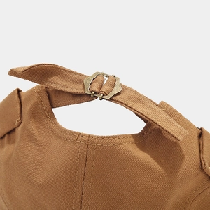 Detailed close-up of the vintage adjustable bronze metal buckle on dark brown canvas cap