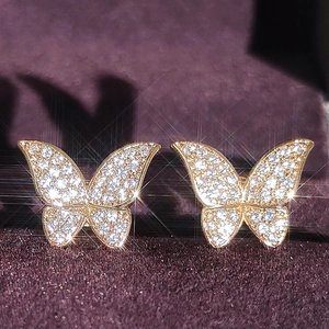 Elegant gold butterfly stud earrings with sparkling white cubic zirconia on purple velvet