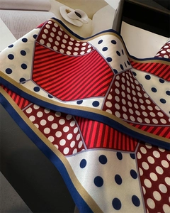 Close-up of silk scarf with navy polka dots and red stripes on a lifestyle background