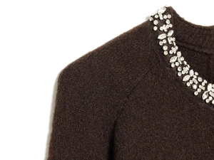Detailed close-up of brown knit sweater with luxury crystal beadwork on the neckline