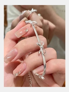 Detailed view of silver bow-shaped elements on a flat snake chain bracelet with adjustable link