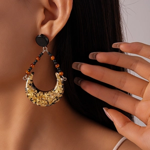 Detailed close-up of retro crescent earrings with gold leaf in resin on model