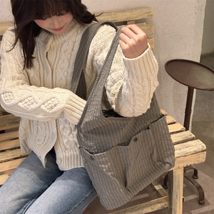 Detail of grey checkered tote bag with metal snap pockets on fabric material