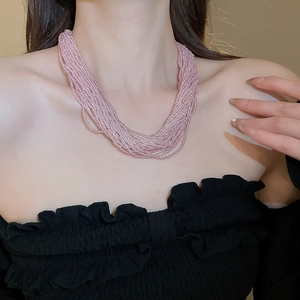 Detail of multi-layered pink beaded necklace on model neck with black top