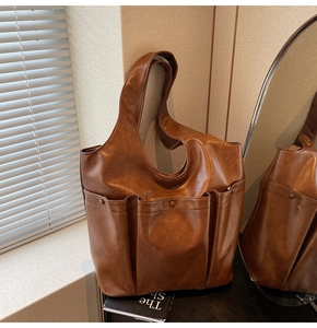 Detail view of a vintage brown PU leather bucket bag with multiple front pockets and texture