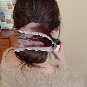 Close-up of velvet pleated scrunchie in mauve with soft texture in low bun hairstyle
