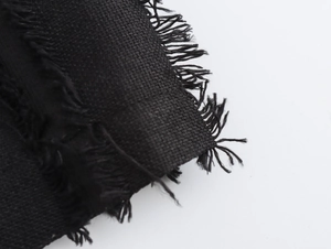 Gros plan sur la texture du lin noir et les détails de franges d'une robe croisée