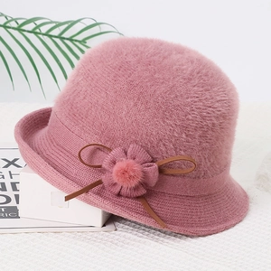Detailed view of pink faux mink fur winter hat with knit floral and bow embellishments
