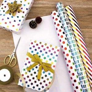 Close-up of birthday gift wrapping paper with gold foil patterns and matching ribbons