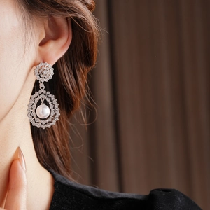Detail of vintage silver flower earring with zircon stones and white pearl drop on model