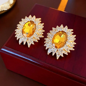 Detail of vintage sunburst earrings with yellow gemstones and rhinestones on a wood box