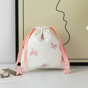 Detail of pink bow pattern on cream canvas drawstring bag with woven cords