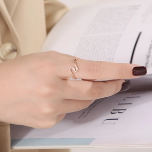 Close-up of a minimalist rose gold wave ring worn on the index finger for a stylish look
