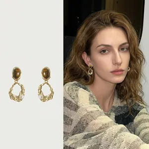 Detail of vintage gold geometric earrings with brown stones and pearls on an Asian model