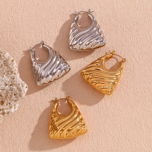 Detail of gold and silver chunky hoop earrings with wavy ripple texture on stone