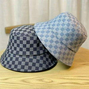 Detail of woven checkerboard denim bucket hats in navy and light blue on a wooden surface