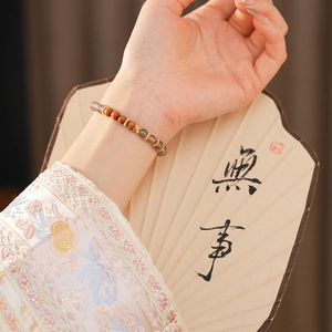 Détail d'un bracelet en perles chinoises avec bois de santal, agate et breloques dorées
