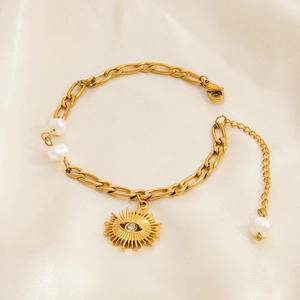 Detail of 18K gold Figaro chain bracelet with starfish, evil eye charm and pearls