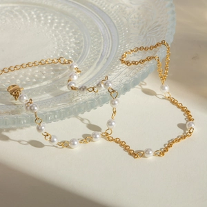 Elegant 18k gold stainless steel chain with white pearls on a glass tray