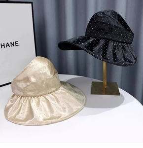 Detail of wide brim sun visors in black and gold satin with shimmering rhinestone accents
