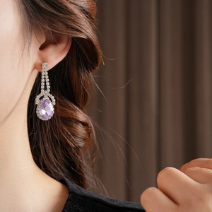 Dettaglio di un orecchino in argento con gemma a goccia viola e cristalli brillanti
