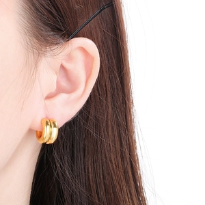 Gros plan de boucles d'oreilles doubles créoles plaquées or 18K sur l'oreille d'une femme