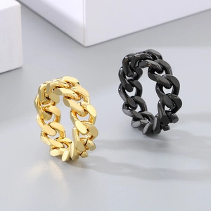 Detail of Cuban link chain rings in polished gold and black finishes on neutral background