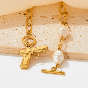 Goldene Perlenkette mit Pistolenanhänger und OT-Verschluss auf Steinfundament