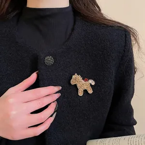 Glückspferd-Brosche mit roten und goldenen Strasssteinen auf einem Tweed-Blazer