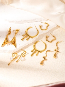 Macro detail of gold vintage flower and heart earrings on a white stone background