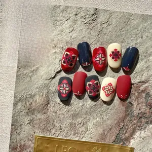 Macro detail of bohemian mandala nail stickers in vintage red and navy blue on stone