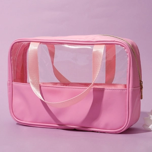 Macro view of pink transparent PVC toiletry bag showing golden zipper and pink handle detail