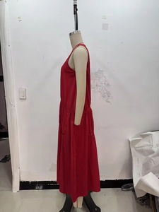 Vue latérale d'une robe midi rouge sans manches avec des plis à la taille sur mannequin