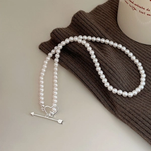 Detail of white pearl necklace with silver heart and arrow OT toggle clasp on knit