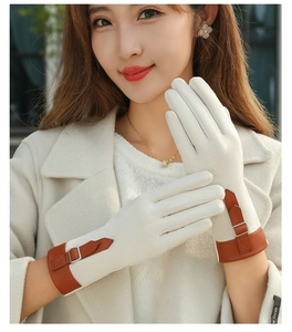 Close-up of beige suede gloves featuring a brown leather strap and metal buckle detail