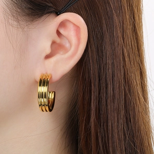 Macro side view of gold C-shaped triple-layer hoop earrings with high-polished metal finish