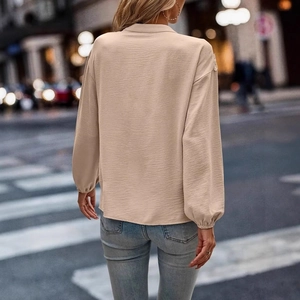 Rear view of elegant beige long-sleeve blouse with delicate lace stitching details