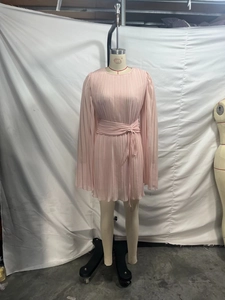 Detail of pink pleated chiffon dress featuring long flared sleeves and matching waist belt