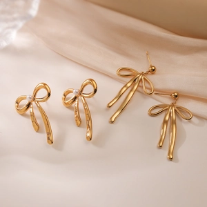 Elegant 18K gold-plated bow earrings with white pearls on a soft silk background
